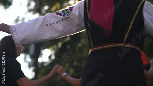 People Join Hands and Dance in Slow Motion with Beautiful Golden Backlit Sun. Traditional Dancing in Bulgaria. photo