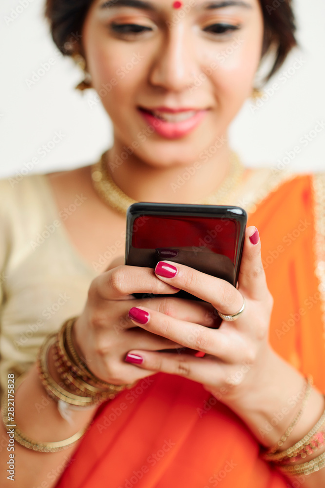 Hands of young smiling Indian woman reading text message from her friend Hands of young smiling Indian woman reading text message from her friend