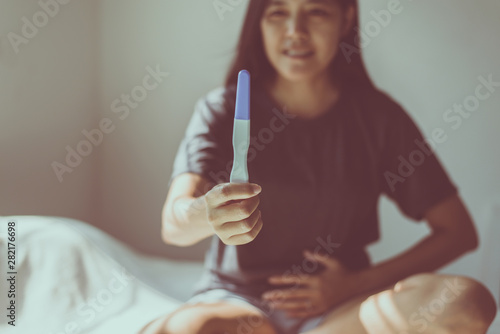 Happy asian woman hands holding pregnancy test after testing  in her bedroom