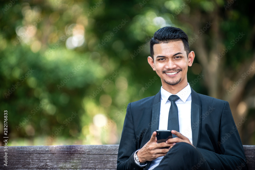 Malay Businessman Texting on his Smartphone Malay Businessman Texting on his Smartphone