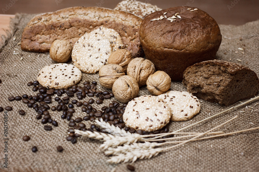 Many kinds of whole wheat bread, sesame cookies, walnuts and coffee beans and wheat spikelets are laid out on a coarse burlap. The concept of a healthy Breakfast. Image still life and selective focus. Many kinds of whole wheat bread, sesame cookies, walnuts and coffee beans and wheat spikelets are laid out on a coarse burlap. The concept of a healthy Breakfast. Image still life and selective focus.