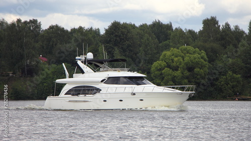 Big white beautiful luxury motor yacht floating on river on summer day, motorboat cruise