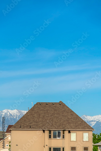 House exterior with blue sky and snow capped mountain background on a sunny day © Jason