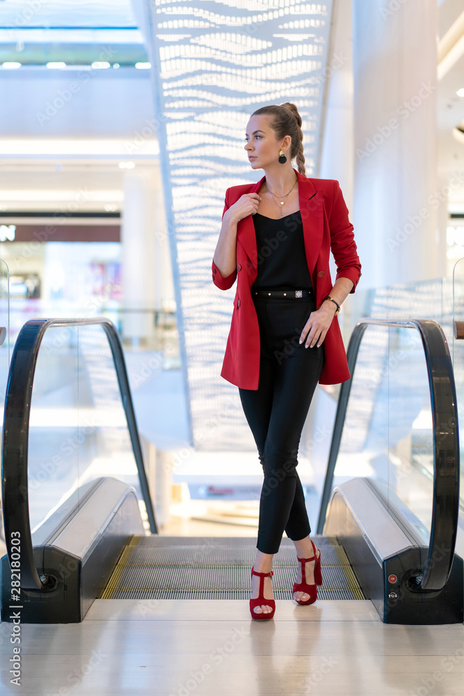 Caucasian girl in red jacket, shoes and black pants. Hairstyle pigtail