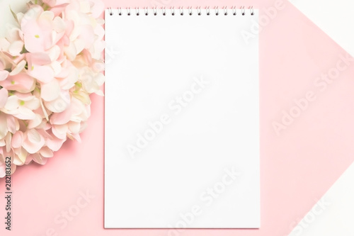 Festive background in pastel colors branch of delicate artificial hydrangea on a pink background with a notebook for writing the text of congratulations with mockup with copy space © Светлана Евграфова