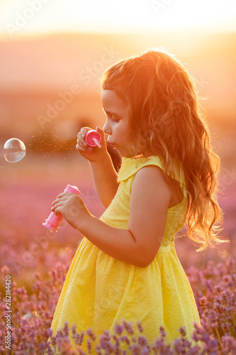 Obraz na płótnie A child with soap bubbles. Little girl in a field with flowers.
