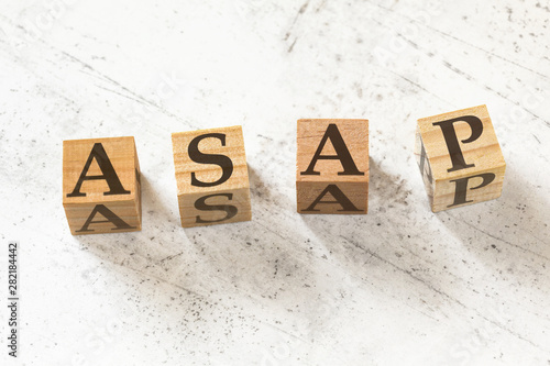 Four wooden cubes with letters ASAP (meaning As soon as possible) on white working board. photo