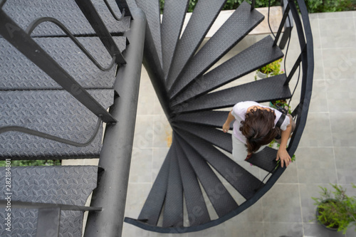 Backgrounds Woman walking down Black spiral staircase