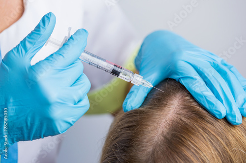 The doctor cosmetologist making mesotherapy injections in woman's head for stronger and healthier hair. photo