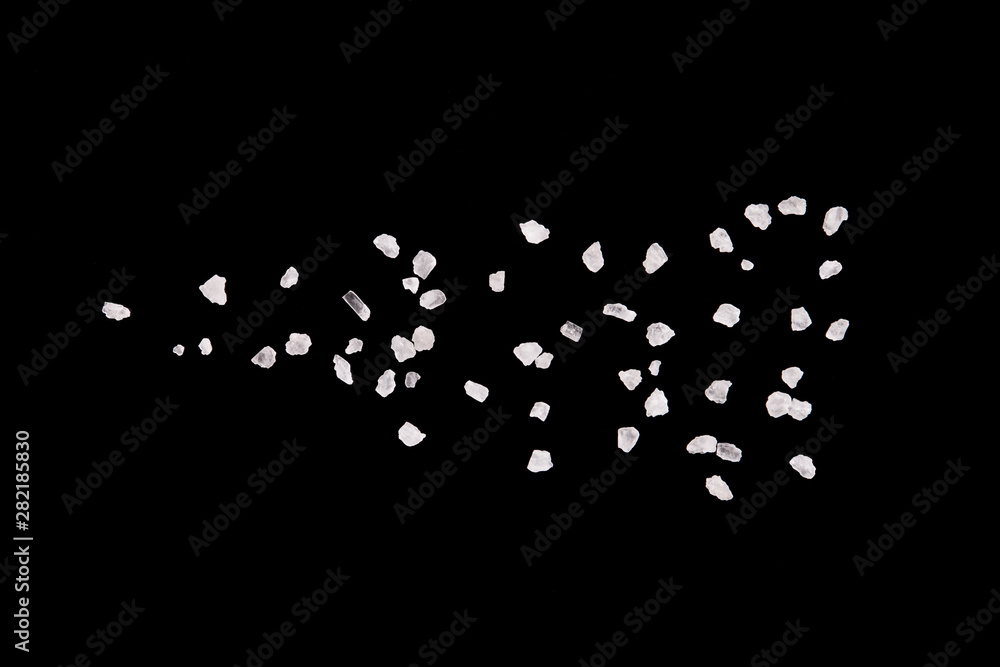 Salt crystals on a black background. Salt crystals close up. Scattered salt particles.