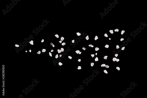 Salt crystals on a black background. Salt crystals close up. Scattered salt particles.