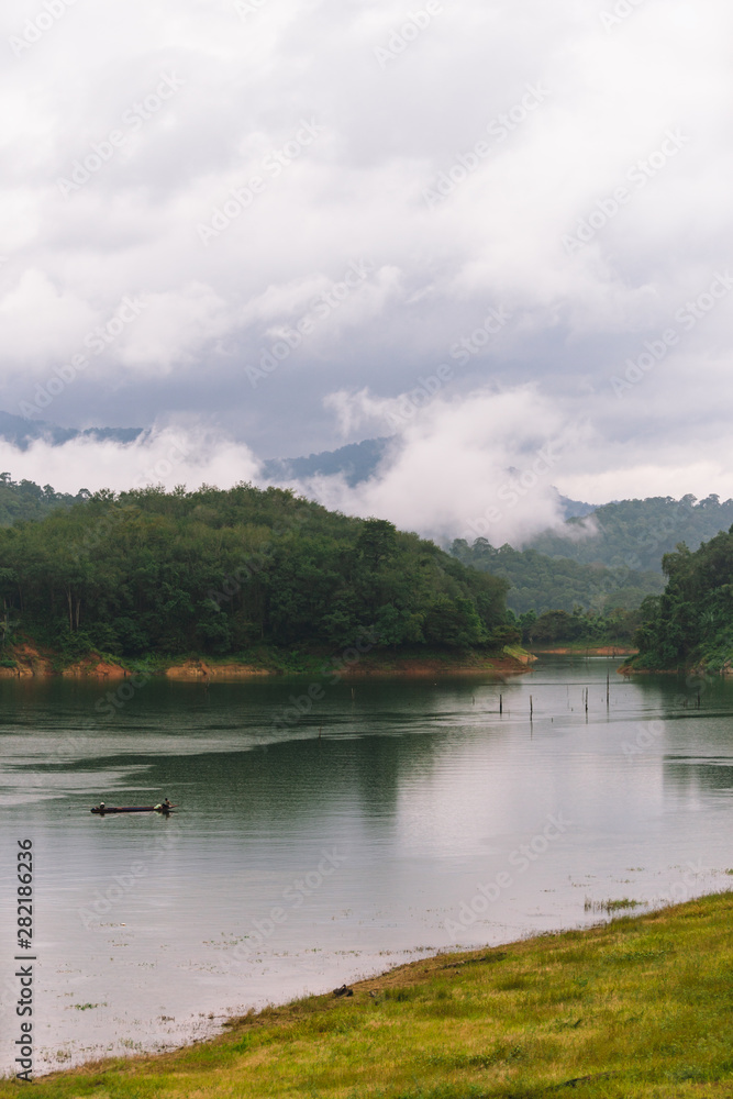 Fisherman and small fishing boat and floating in Bang Lang reservoir in the rain. Fisherman and small fishing boat and floating in Bang Lang reservoir in the rain.