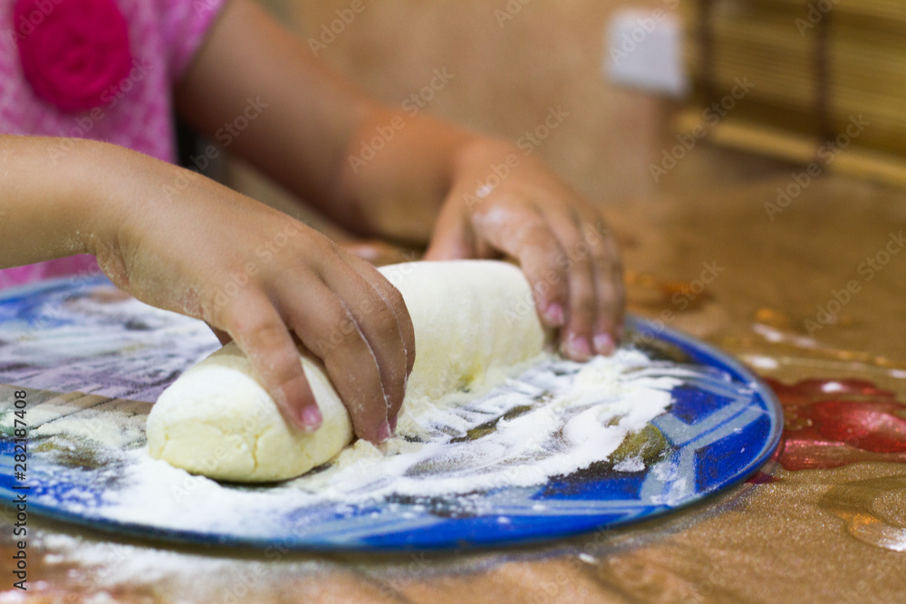 Child hands preparing dough with flour on the kitchen table. Homemade cakes for bread or pizza. Girl sculpts cheesecakes. Food for a snack and Breakfast. Child hands preparing dough with flour on the kitchen table. Homemade cakes for bread or pizza. Girl sculpts cheesecakes. Food for a snack and Breakfast.