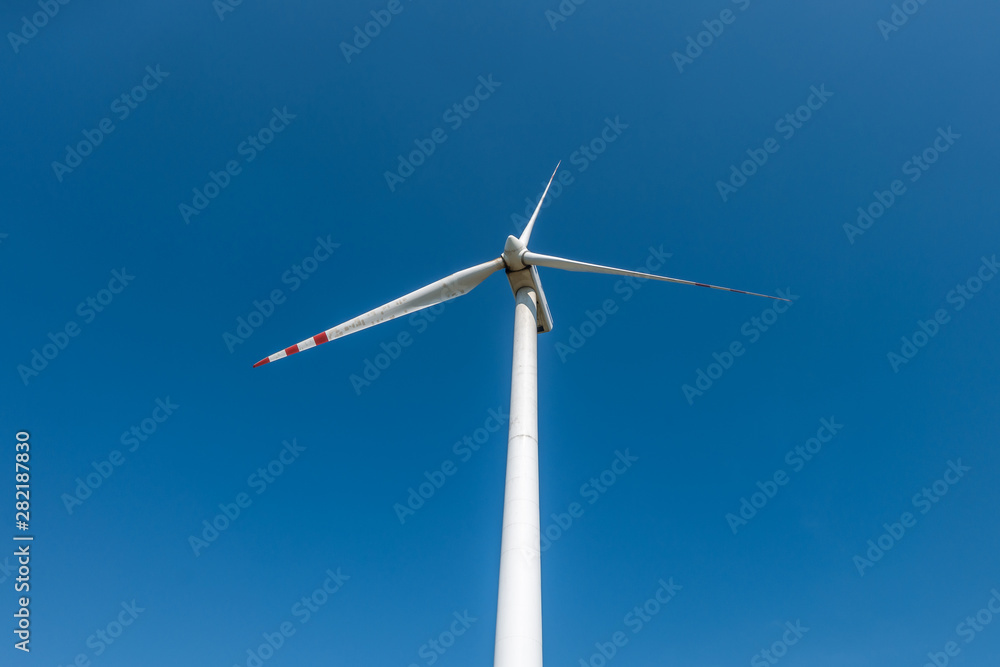 rotating blades of a windmill propeller on blue sky background. Wind power generation. Pure green energy. rotating blades of a windmill propeller on blue sky background. Wind power generation. Pure green energy.
