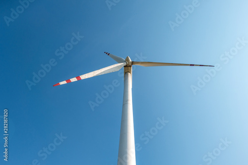 rotating blades of a windmill propeller on blue sky background. Wind power generation. Pure green energy.
