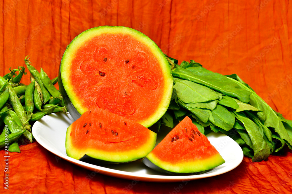 One chopped watermelon in a plate with vegetables on the side One chopped watermelon in a plate with vegetables on the side