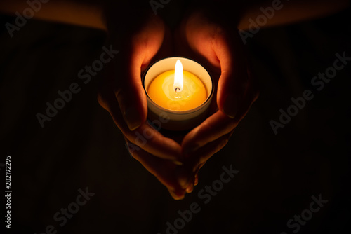Lighted candle in female hands in the dark on the black background. Diwali, Obon festival 