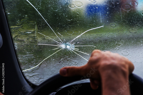 Broken windshield of a car. A web of radial splits, cracks on the triplex windshield. Broken car windshield, damaged glass with traces of oncoming stone on road or from bullet trace in car glass photo