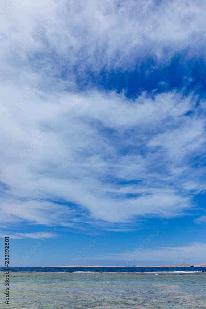 Beautiful seascape. Vertical color photography of blue sky and Egyptian island seen far away in distance at horizon. 