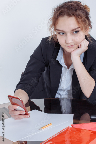 Portrait of young beautiful smiling casual woman sitting at office desk enjoying her cup of coffee while working or studying on laptop computer at small home office or in the student dorm. Indoors photo