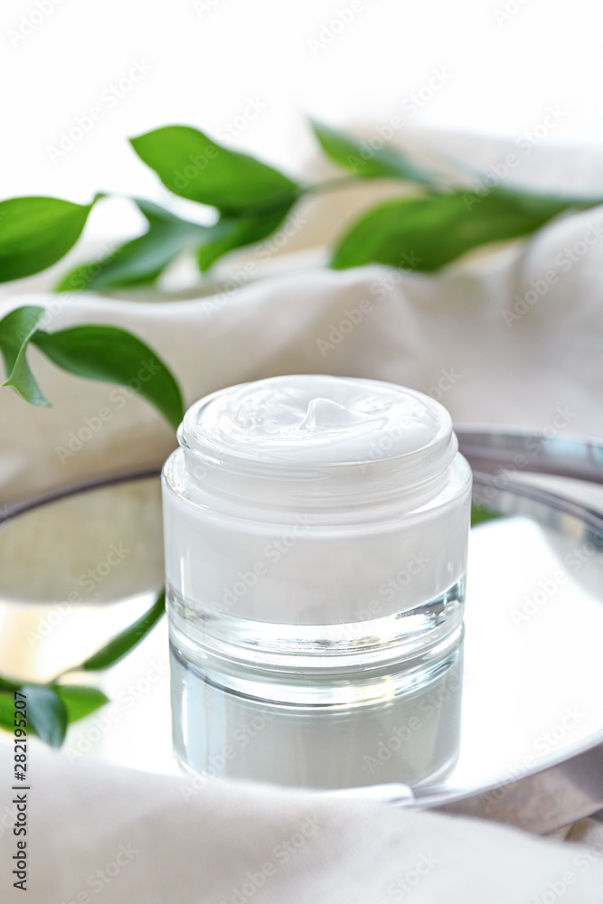 Jar of body cream with herbal extract on table Jar of body cream with herbal extract on table