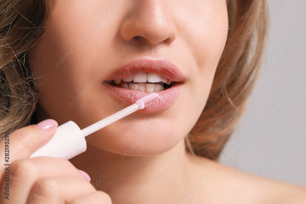 Beautiful young woman applying lipstick, closeup Beautiful young woman applying lipstick, closeup