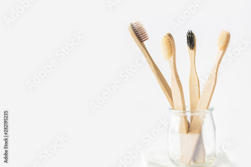 Charcoal wooden bamboo toothbrushes in glass cup on white background. Zero waste plastic free eco friendly reusable materials for teeth hygiene health. Poster banner