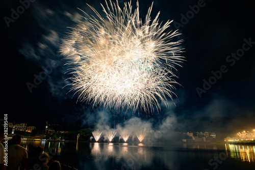 Beautiful pyrotechnic fireworks at night over the water. Celebration.