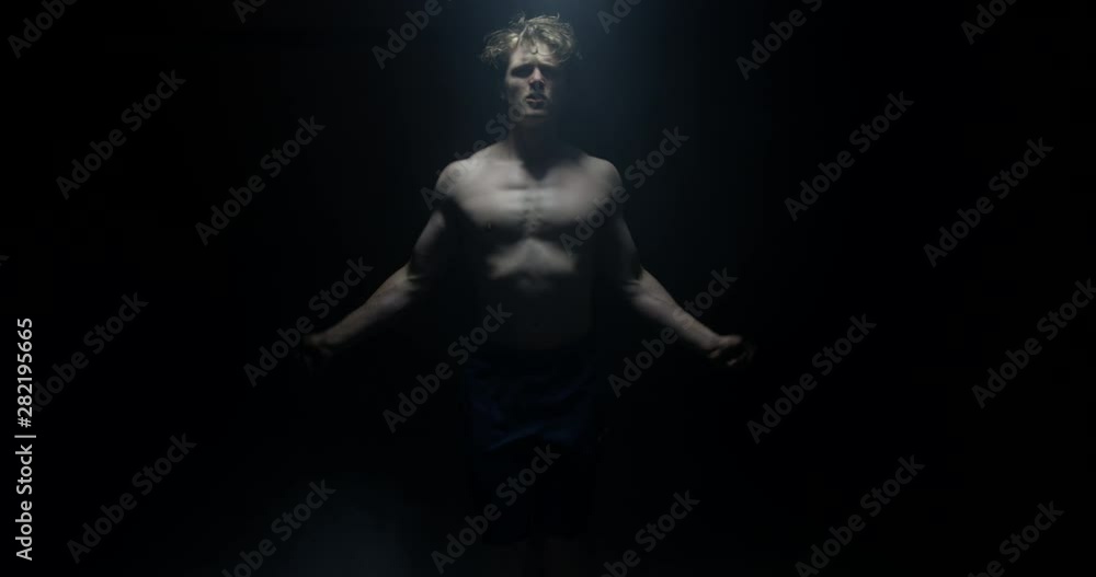 Active Male Model Skipping And Training Exercising In A Dark Background Looking At Camera Active Male Model Skipping And Training Exercising In A Dark Background Looking At Camera