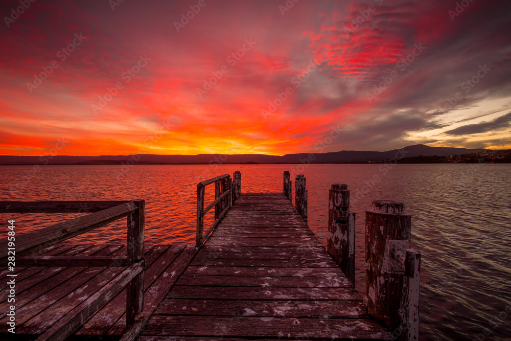 Burning red sunset  on the lake with timber jetty