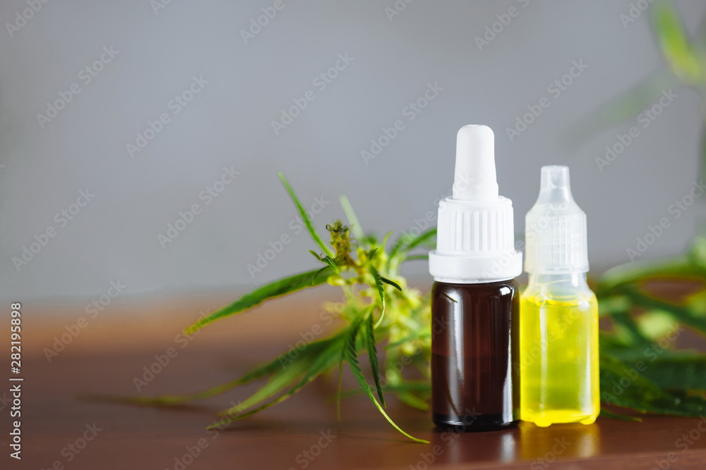 Hemp plant herbal pharmaceutical CBD oil from jar. CBD oil bottles cannabis extract tincture liquid on wooden table. Medical marijuana concept Hemp plant herbal pharmaceutical CBD oil from jar. CBD oil bottles cannabis extract tincture liquid on wooden table. Medical marijuana concept