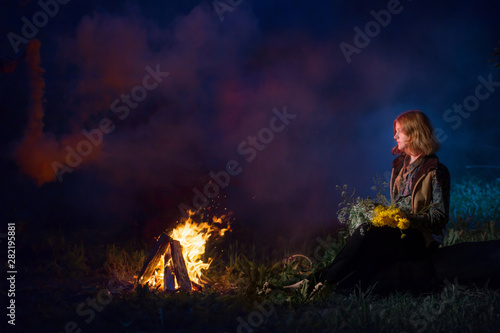 young witch by night fire in forest