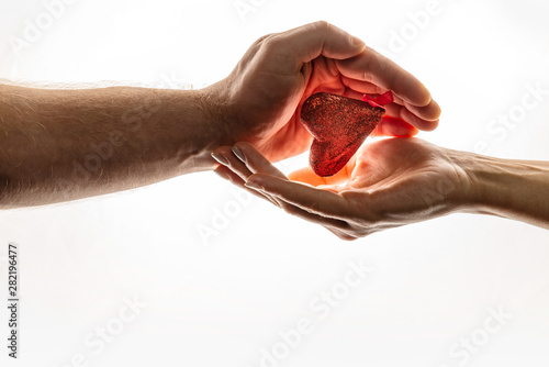 Female and male hands are keeping red heart together. Heart is between hands. World Compassion Day.
