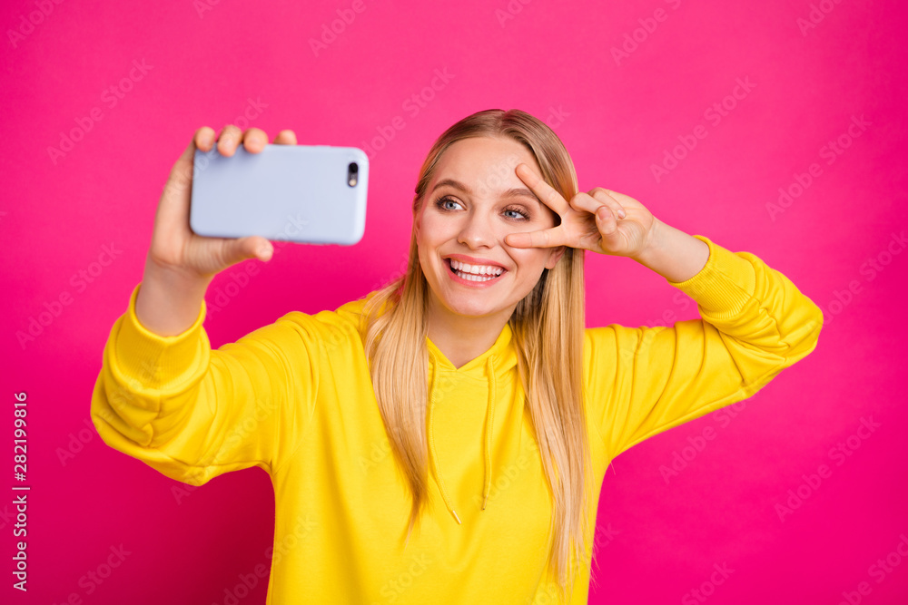 Photo of pretty lady making selfies showing v-sign near eye wear yellow hoodie isolated pink background Photo of pretty lady making selfies showing v-sign near eye wear yellow hoodie isolated pink background