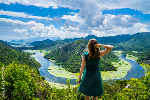 Montenegro, Pretty young woman with long hair standing at crnojevica river water bend, pavlova strana above green valley in national park skadar lake photo