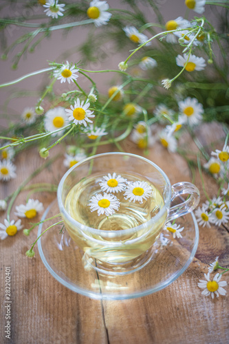 Cup of chamomile herbal tea with flowers on a table. Healthy natural drink.