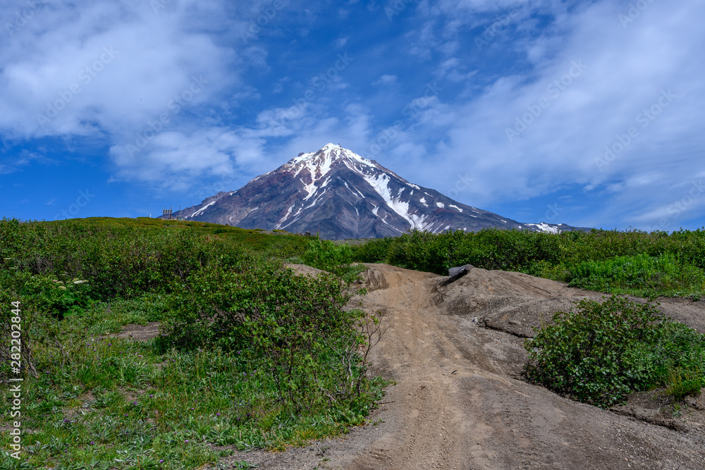 Fototapeta premium Panoramic view of the city Petropavlovsk-Kamchatsky and volcanoes: Koryaksky Volcano, Avacha Volcano, Kozelsky Volcano. Russian Far East, Kamchatka Peninsula.