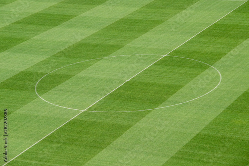 Freshly mowed green grass on the football - soccer field with center lines in the middle.