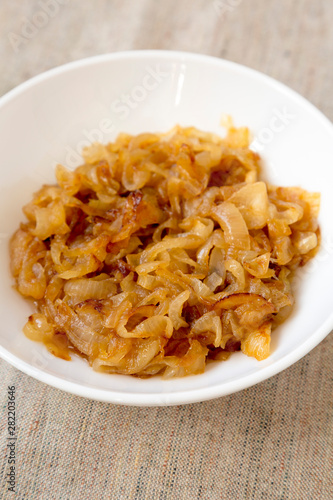 Homemade caramelized onions on a white plate, side view. Close-up.