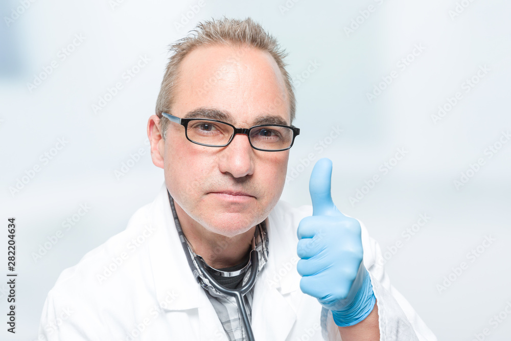seriously looking doctor with medical gloves shows thumbs up seriously looking doctor with medical gloves shows thumbs up
