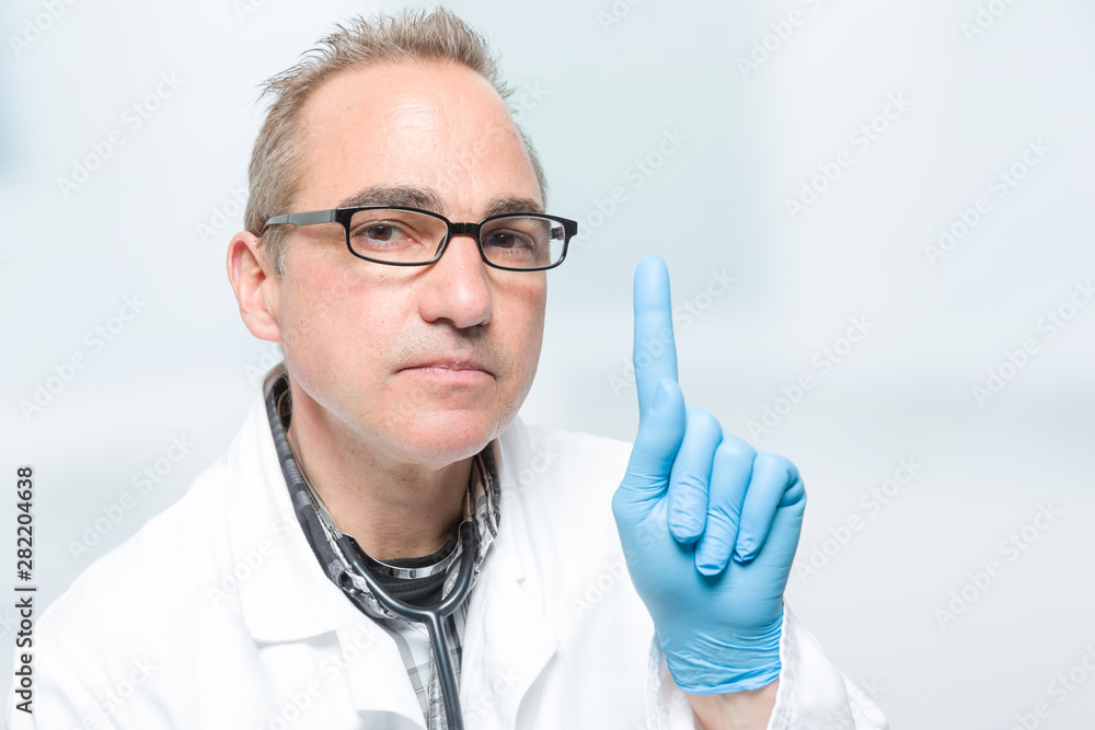 seriously looking doctor is rising his pointing finger seriously looking doctor is rising his pointing finger