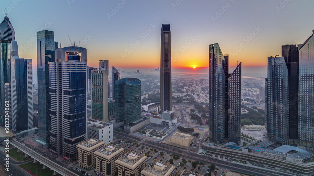 Fototapeta premium Sunrise over Dubai skyline in the morning, aerial top view to downtown city center landmarks timelapse.