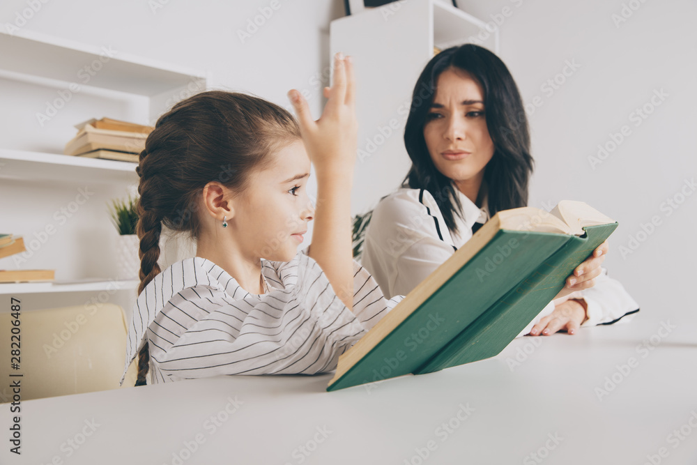 Pretty mother with cute daughter sitting with book in the room at home Pretty mother with cute daughter sitting with book in the room at home