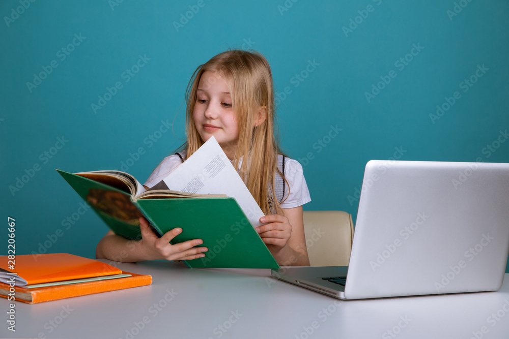 Little girl sitting in the classroom with book infront of computer Little girl sitting in the classroom with book infront of computer