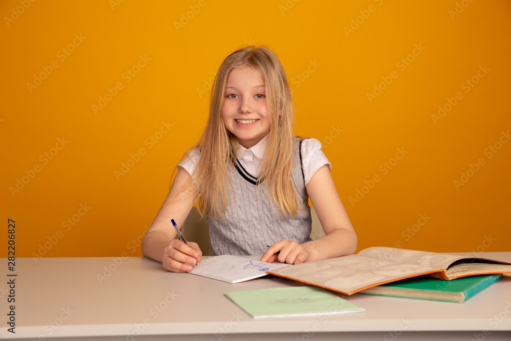 Happy child doing homework sitting isolated the bright yellow background Happy child doing homework sitting isolated the bright yellow background
