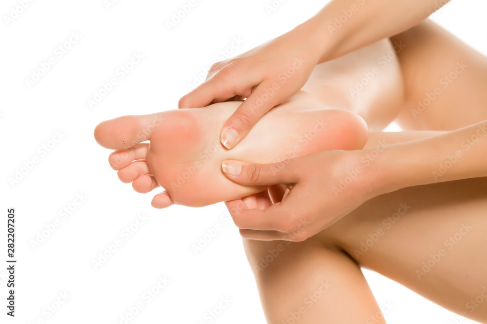 Young woman massaging her tired painful feet. Closeup isolated on white background. Young woman massaging her tired painful feet. Closeup isolated on white background.