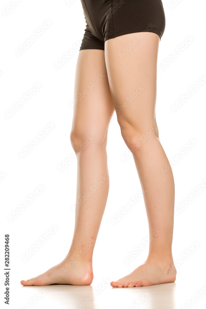 Young woman waxed long naked legs standing on her toes. Isolated on white background side view.