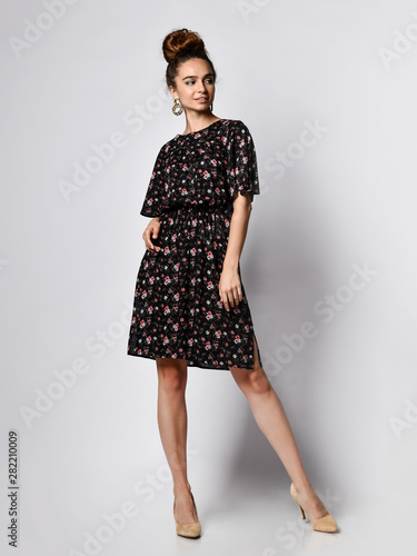 Slim curly female model in a silk pale dress looking at the camera in full growth. Cute girl in romantic clothes is going on a date