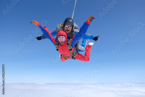 Skydiving. Tandem jump. A strong man and a young woman are falling in the sky.
