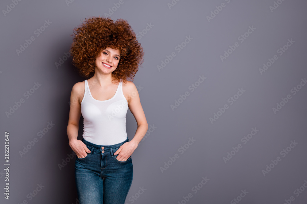 Close up photo of curly hairstyle lady hands pockets toothy beaming smile wear white tank-top jeans denim isolated grey background Close up photo of curly hairstyle lady hands pockets toothy beaming smile wear white tank-top jeans denim isolated grey background